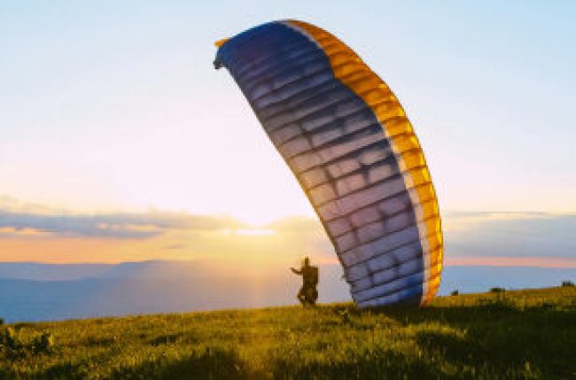 A traveler and a paragliding instructor smiling after landing on Budva’s beach.